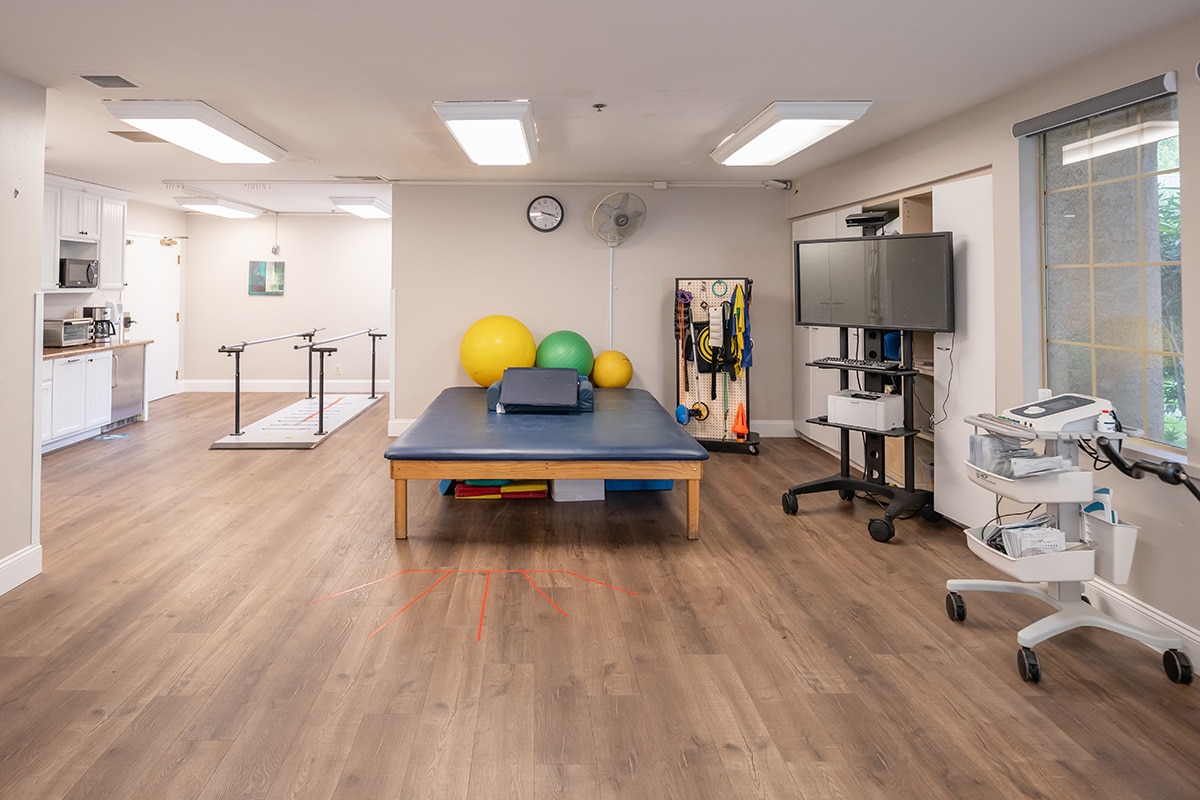 Rehab gym with therapy table and exercise equipment at Arbor Post-Acute.