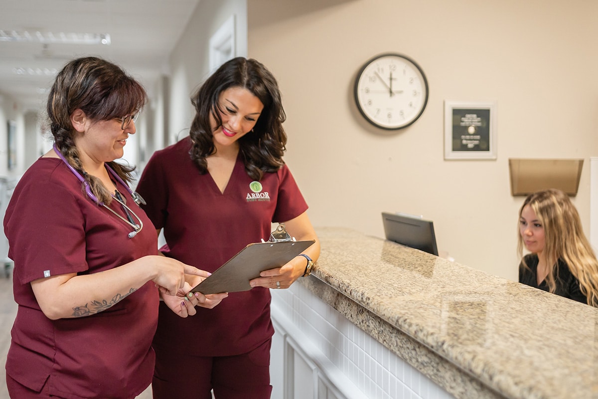 two nurses talking in the hallway at Arbor Post Acute