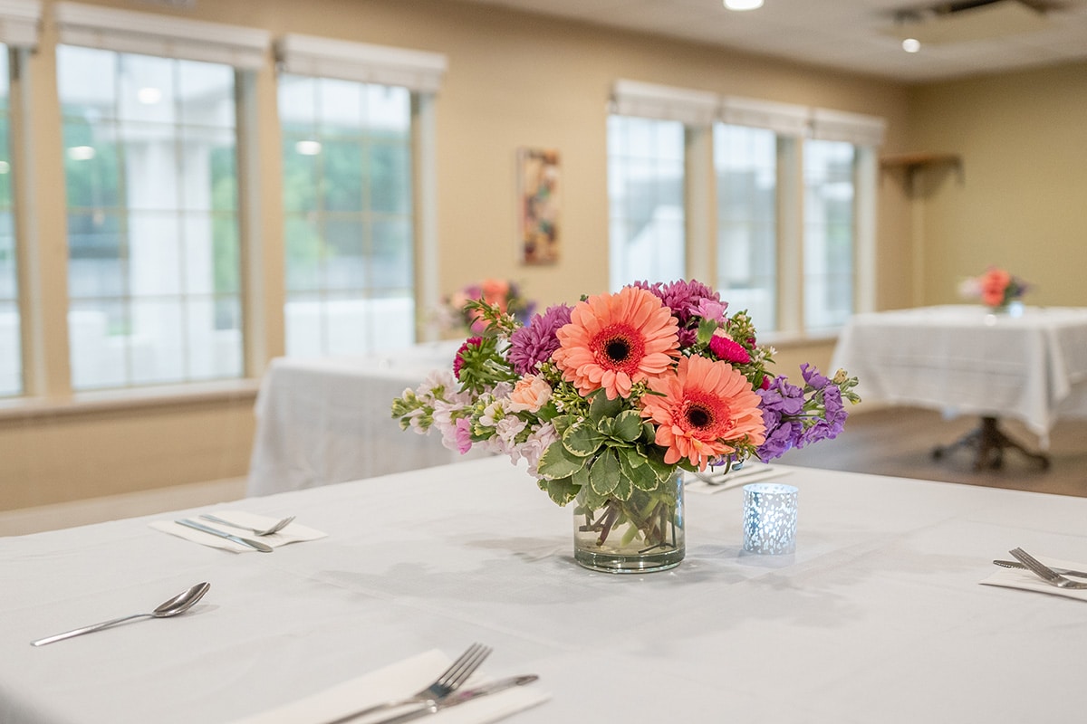 dining area with cut flowers and linen tablecloths at Arbor Post Acute