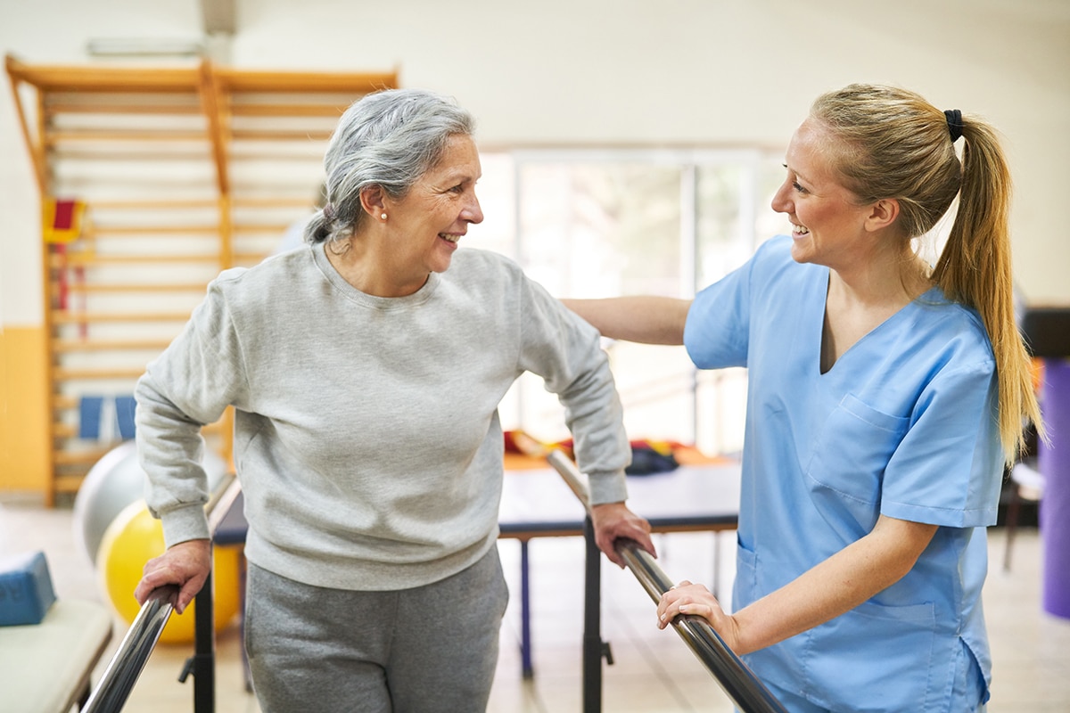 Physiotherapist assisting elderly woman in movement therapy