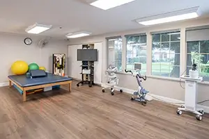 Rehab gym with therapy table and exercise equipment at Arbor Post-Acute.